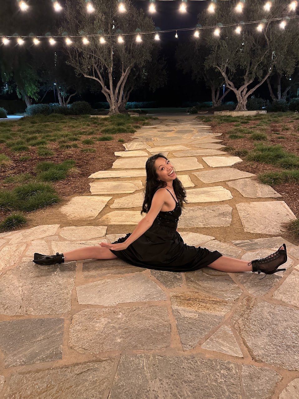 Frances mid-split on a stone path under string lights